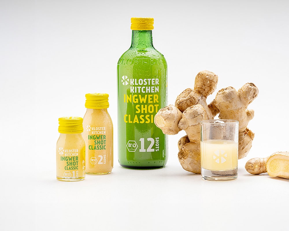 Alle Produkte bildlich dargestellt: Ingwer Shot 30 ml, Ingwer Shot 60 ml Ingwer Shot 360 ml, ein Shot Glas und daneben eine Ingwerknolle
